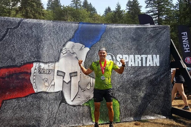 Daniel at the finish line of a Spartan Race, arms raised, medal around his neck