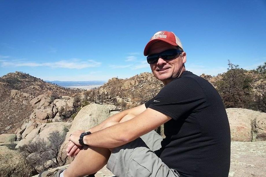 Daniel sitting on a granite summit looking back across a boulder-strewn range